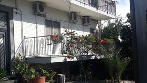 Un edificio de varios pisos con balcones, unidades de aire acondicionado y plantas en macetas.