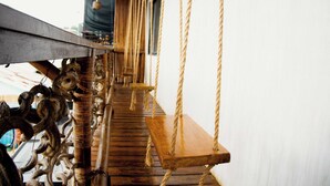A wooden swing suspended by ropes, a metal structure, and a wooden bench. - Happiness Hostel El Nido (El Nido)