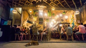 An outdoor seating area with wicker chairs and tables, a dog lying on the ground, and a sign advertising the healthiest breakfast. - Happiness Hostel El Nido (El Nido)