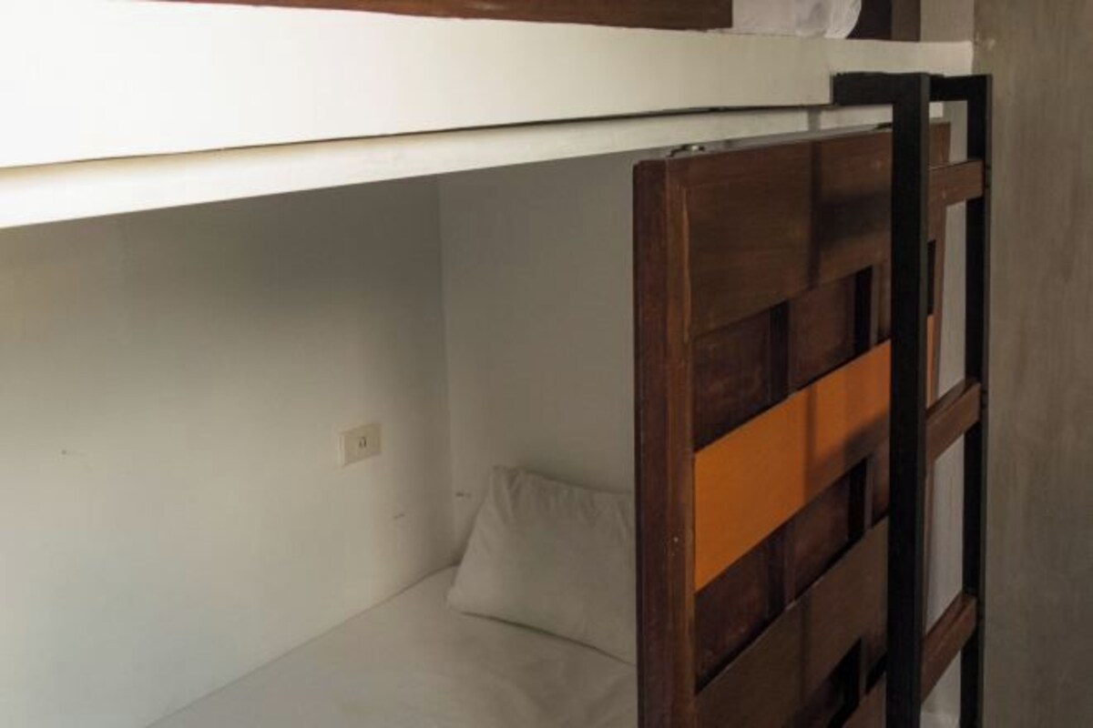 A bunk bed with a wooden headboard and a white mattress.