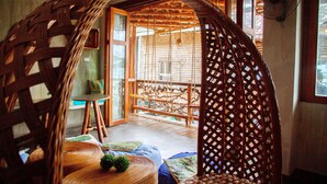 A room with a woven partition, a fan, and a view of the outside. - Happiness Hostel El Nido (El Nido)