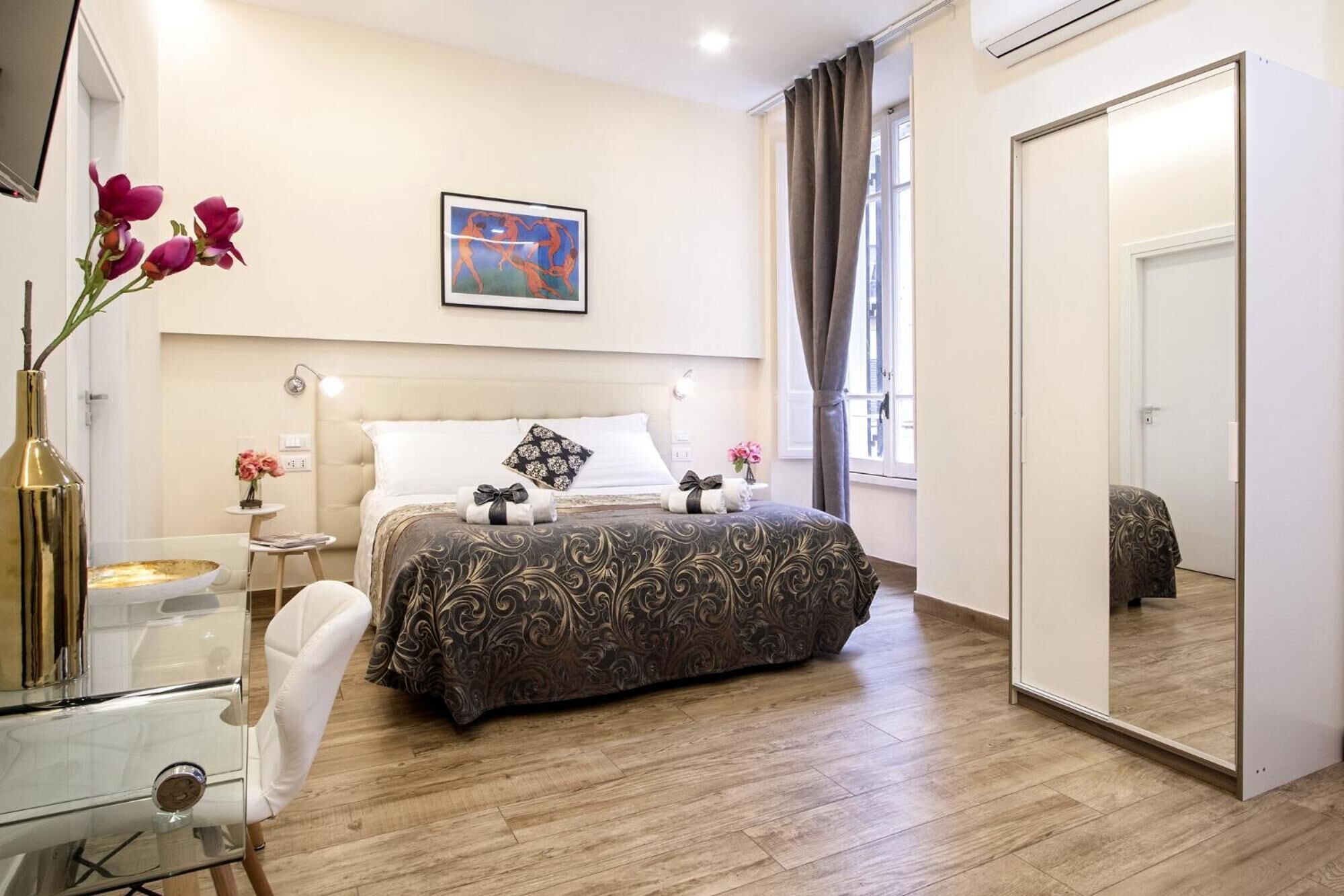 Un dormitorio moderno con una cama grande, una mesita de noche, un espejo y una ventana con cortinas.