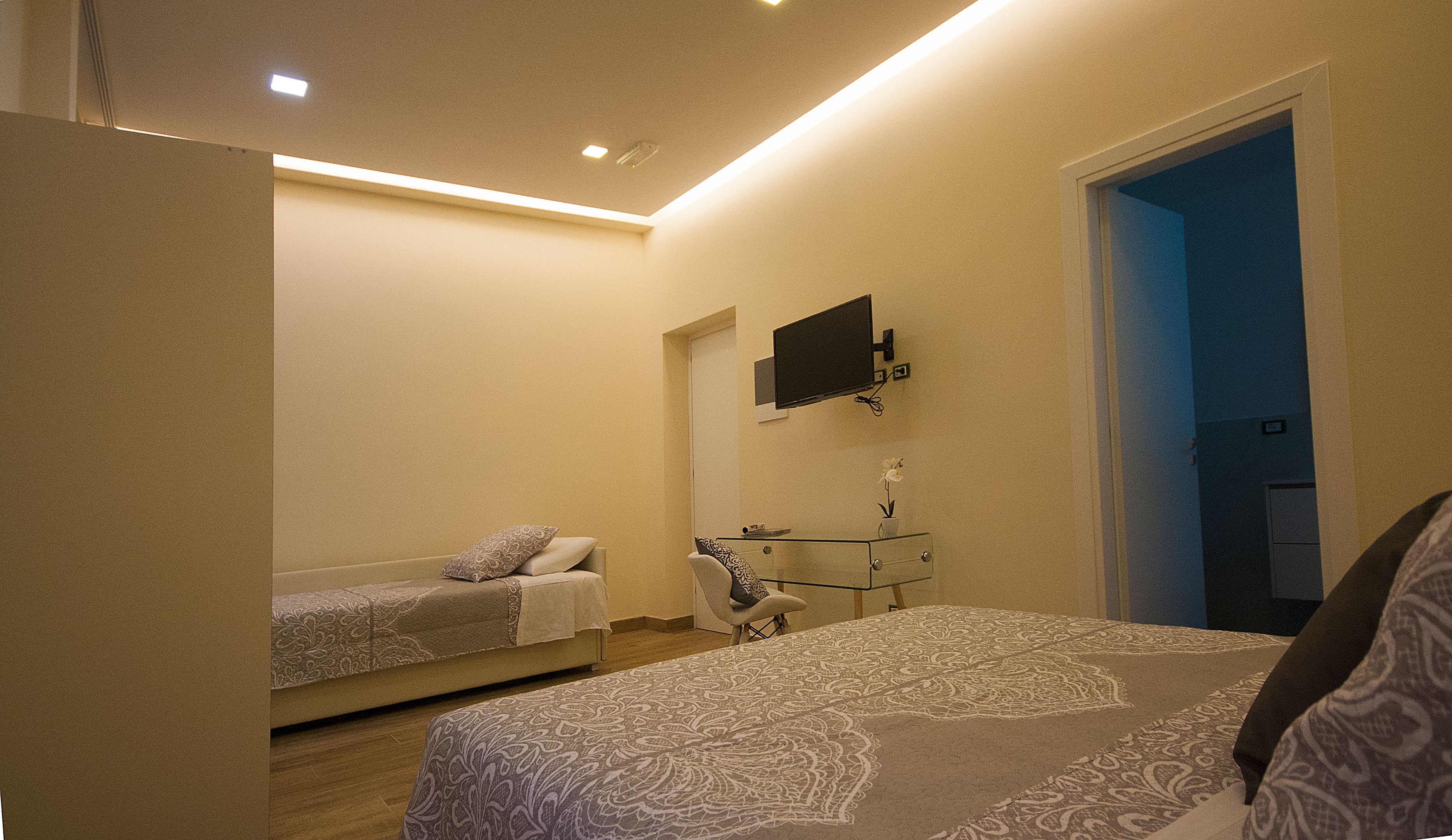 A bedroom with a bed, a sofa, a TV, and a desk.
