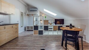 A modern kitchen with wooden cabinets, a dining area with a table and chairs, and a TV in the background. - Casa San Vito (Rijeka)