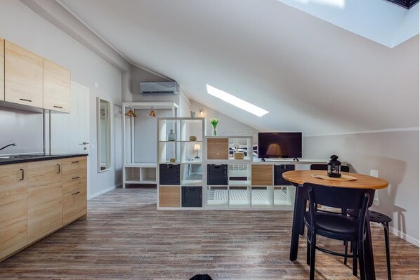 A modern kitchen with wooden cabinets, a dining area with a table and chairs, and a TV in the background. - Casa San Vito (Rijeka)
