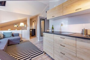 A modern kitchen with light wood cabinets, a black countertop, and a striped rug. - Casa San Vito (Rijeka)