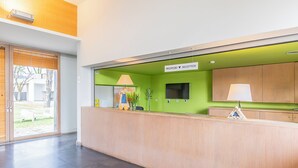 A reception area with a green wall, a reception desk, a TV, and a sign that reads 'RECEPCÃO' (Reception). - HI Viana Castelo - Pousada de Juventude - Hostel (Viana do Castelo)