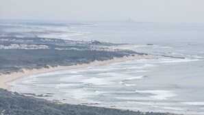A coastal landscape with a beach, waves, and a distant cityscape. - HI Viana Castelo - Pousada de Juventude - Hostel (Viana do Castelo)