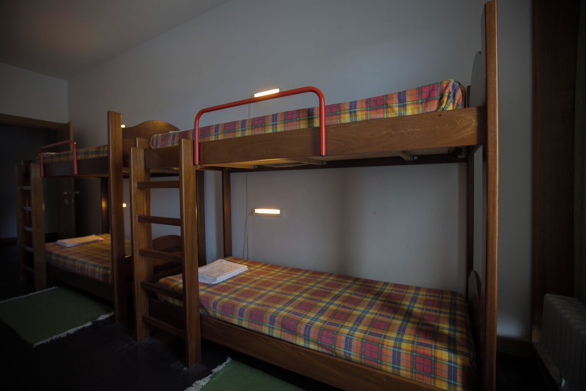 A dormitory room with bunk beds, a wooden ladder, and a small table.