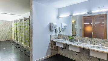 Un baño moderno con encimeras de mármol, un espejo grande y varios secadores de manos.