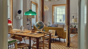 A cozy living room with a wooden table, chairs, a globe, and a yellow sofa.