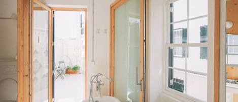 A modern bathroom with a freestanding bathtub, a shower, and a window providing natural light.