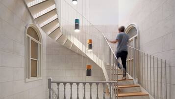 A person ascending a spiral staircase with ornate railings and patterned floor tiles.