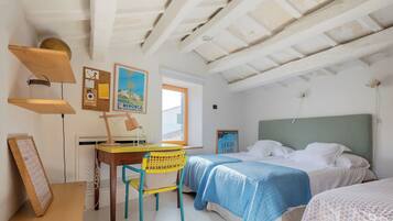 Un dormitorio con una cama, un escritorio y una silla. Hay un cartel en la pared y una ventana.