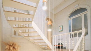 A staircase with white railings and wooden steps, leading to a landing with a view of a tiled floor and a door with glass panels.