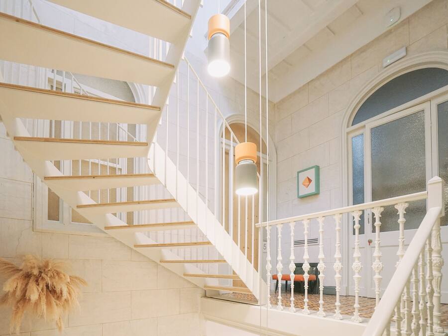 A staircase with white railings and wooden steps, leading to a landing with a view of a tiled floor and a door with glass panels.