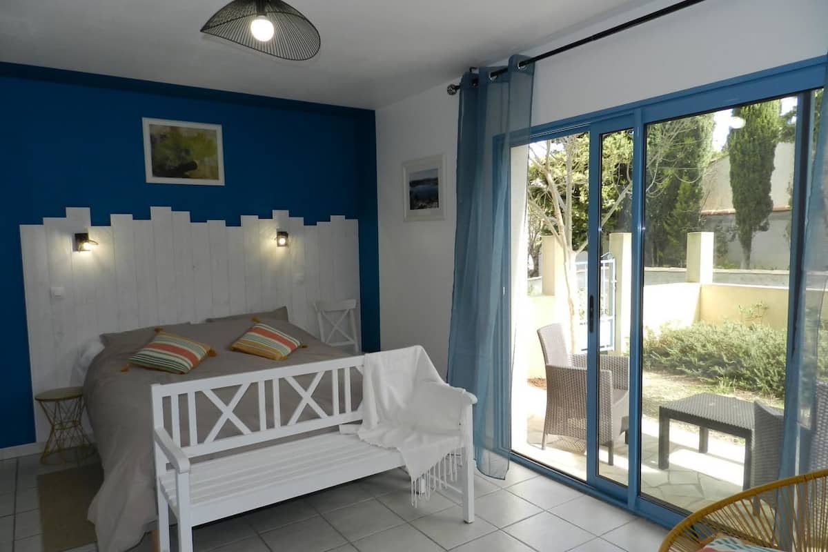 Een slaapkamer met een bed, een witte bank, een plafondlamp en uitzicht op het omliggende landschap.