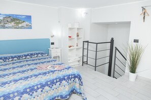 Ein Schlafzimmer mit einem Bett, einem weißen Kleiderschrank, einem kleinen Schreibtisch und einer Treppe.