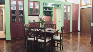 A dining area with a wooden table and chairs, green and brown cabinets, and a vase with flowers.