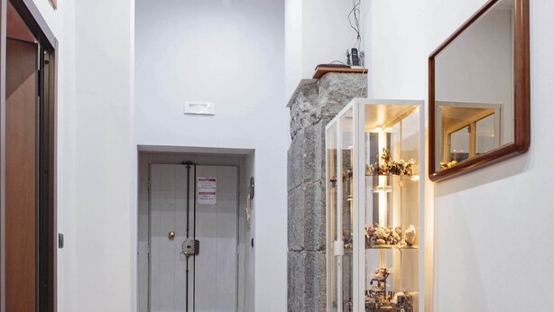 A hallway with a red carpet, a glass display cabinet, and a mirror on the wall.