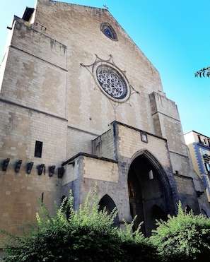 A historic building with a large arched entrance, a prominent circular window with intricate designs, and a cross at the top. - Palazzo Carafa della Spina - Charme (Naples)