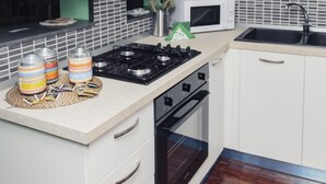 A modern kitchen with white cabinets, a microwave, a gas stove, and a sink.