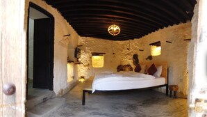 Un dormitorio rústico con cama, cabecero de madera y paredes de piedra.