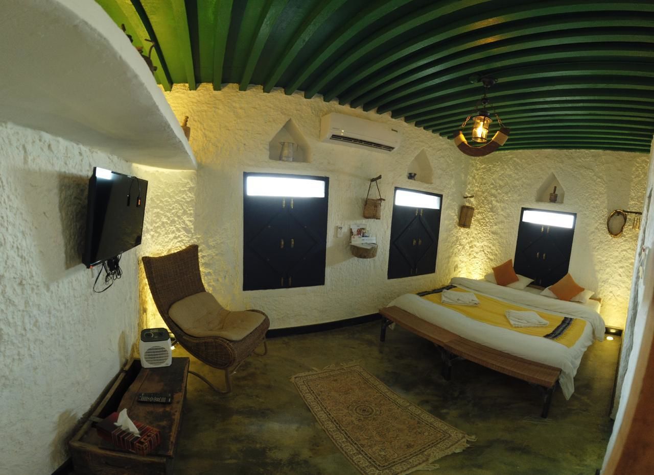 A cozy room with a bed, a chair, a small table, and a television mounted on the wall.