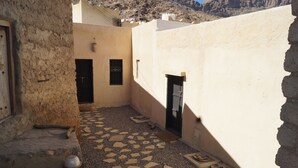 Un patio estrecho con suelo de baldosas, una puerta y un ventanal pequeño.