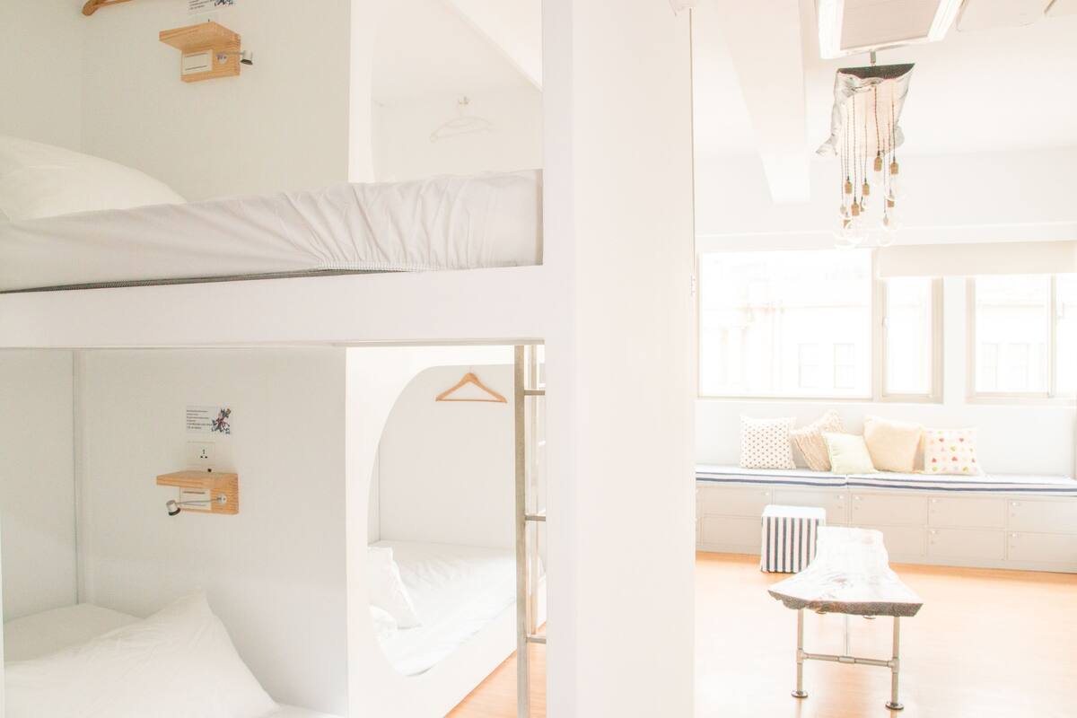 Une chambre avec un lit superposé, un bureau et un luminaire suspendu.