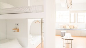 Une chambre avec un lit superposé, un bureau et un luminaire suspendu.
