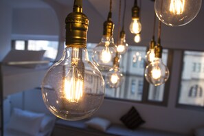 Una habitación con bombillas colgantes de cristal, una cama y una pared con cuadros enmarcados.