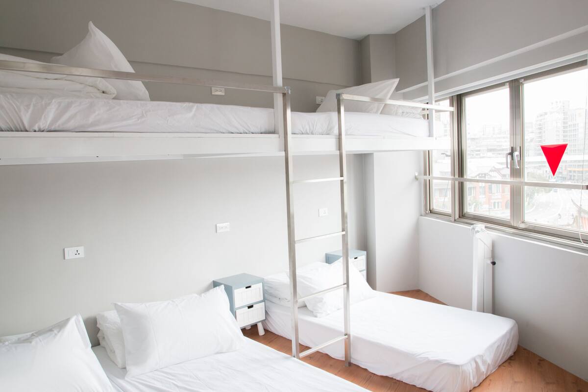 Une chambre avec des lits superposés, une fenêtre et une table de chevet.