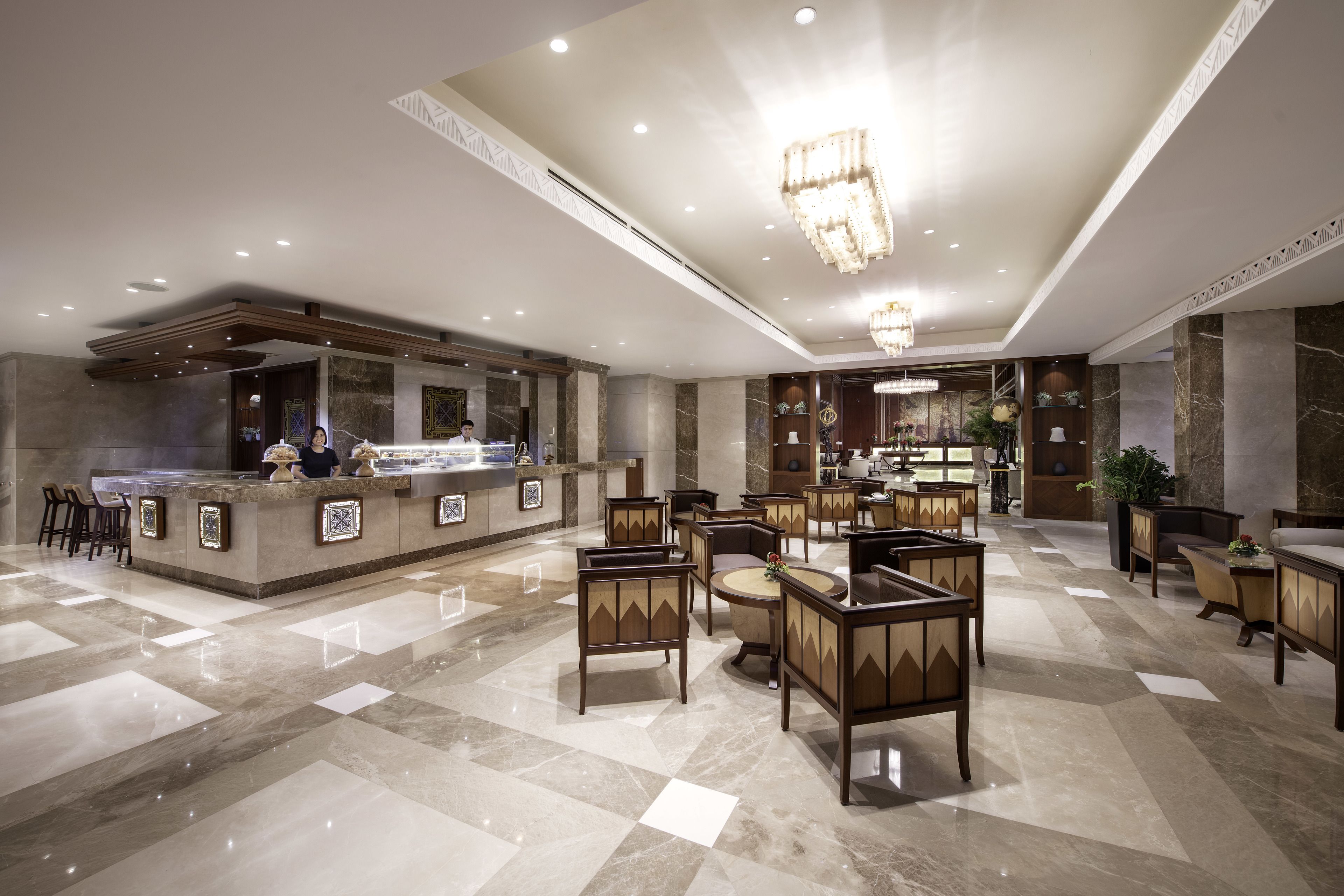 A hotel lobby with a reception desk, seating area, and decorative elements.
