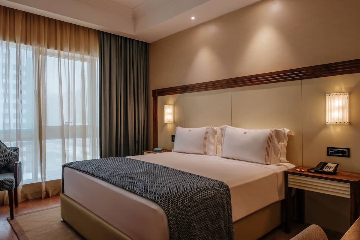 Une chambre d’hôtel avec un grand lit, une table de chevet avec un téléphone et une chaise.