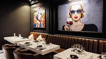 A restaurant with marble-topped tables, brown leather booths, and artwork on the walls.