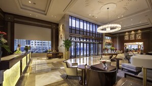Un'ampia hall con pavimento in marmo, una reception, un'area salotto e grandi finestre con vista sulla città.