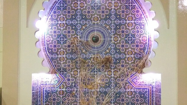 A decorative fountain with intricate tile patterns and a central plant. - Hotel Tiout (Taroudant)