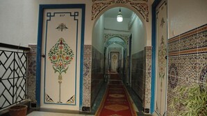 A hallway with intricate tile work, a patterned carpet, and a door with a decorative design. - Hotel Tiout (Taroudant)