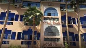 A hotel with a beige facade, blue window frames, and a central arched entrance. - Hotel Tiout (Taroudant)