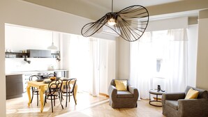 A spacious living area with a dining table, two armchairs, a sofa, and a hanging light fixture. - We Saw Athens (Athens)