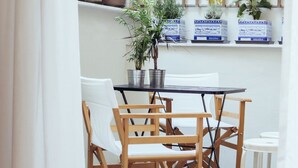 A small dining area with a table and chairs, a potted plant, and a bamboo screen. - We Saw Athens (Athens)