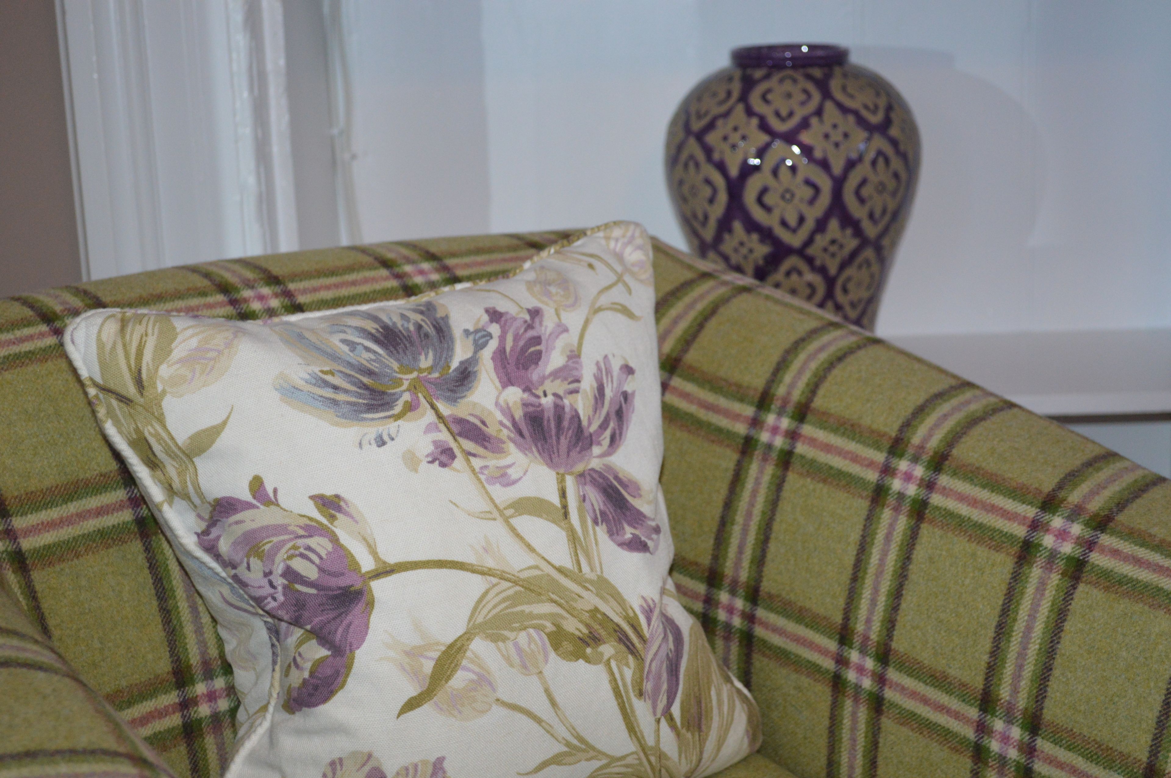 A pillow with a floral pattern on a plaid sofa.