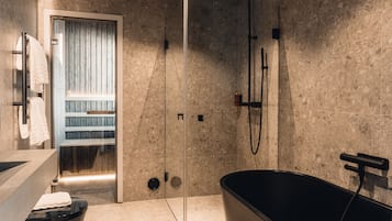 A modern bathroom with a glass-enclosed shower, a freestanding bathtub, and a towel rack.