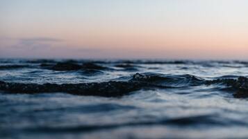 En suddig bild av havet med vågor, troligen tagen under solnedgången eller soluppgången.