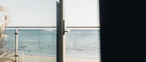 A view from a balcony with a wooden deck and a glass door leading to a room.
