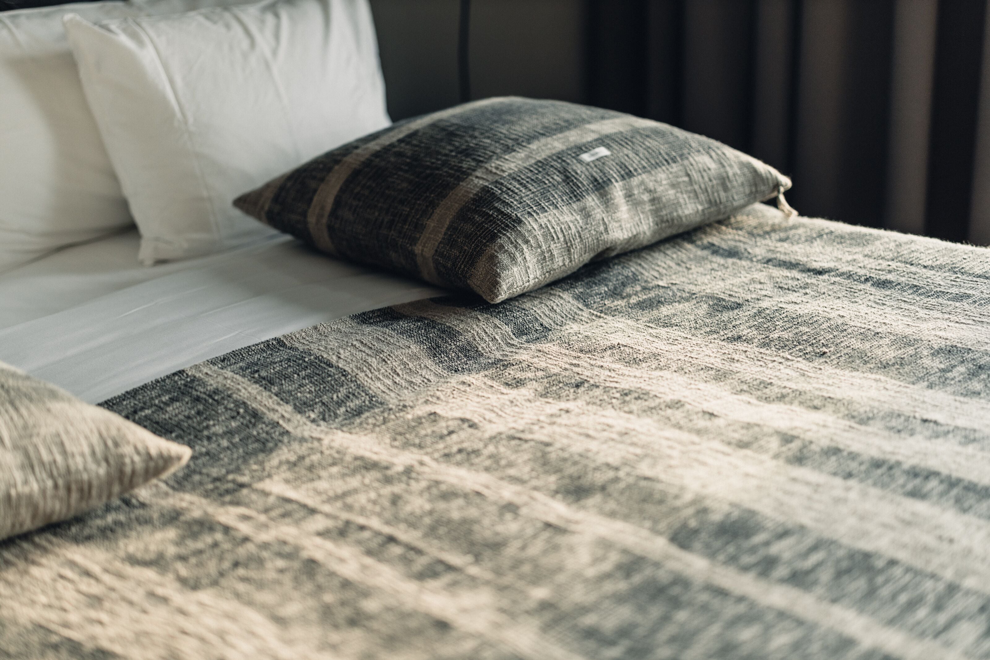 A bed with a striped blanket and two pillows, one white and one gray.