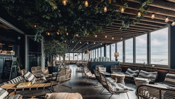 A spacious indoor seating area with wicker furniture and large windows overlooking the sea. - Ocean Hotel (Falkenberg)