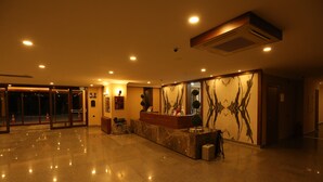 Un vestíbulo amplio con una recepción, una silla de ruedas y un gran mural abstracto en la pared.