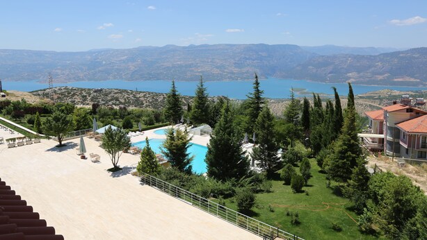 Un resort con piscina, rodeado de árboles y vistas a montañas y un lago.
